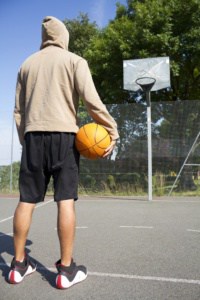 Man with basketball in front of in-ground hoop