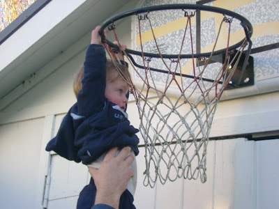 Little boy hanging from a basketball hoop